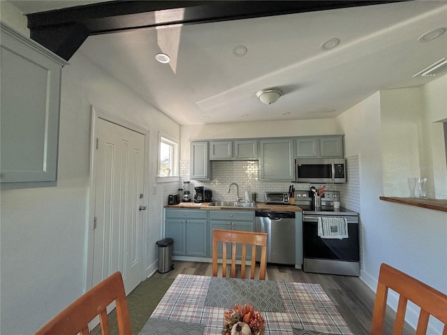 kitchen with dark hardwood / wood-style flooring, stainless steel appliances, tasteful backsplash, and sink