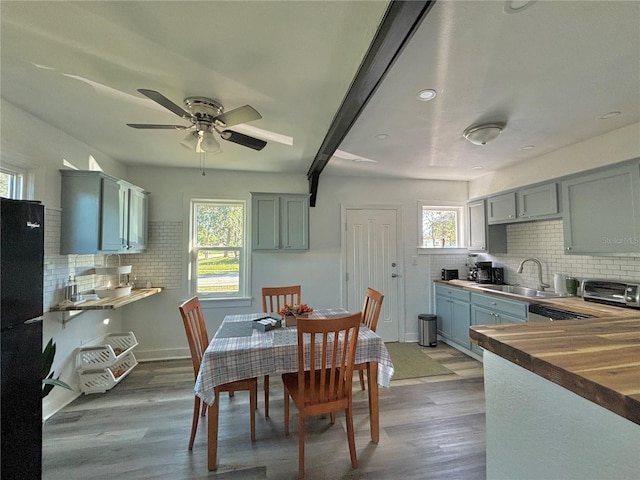 dining room featuring beamed ceiling, wood-type flooring, ceiling fan, and sink