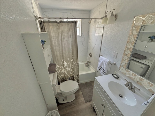 full bathroom with vanity, a textured ceiling, shower / bath combo with shower curtain, hardwood / wood-style floors, and toilet