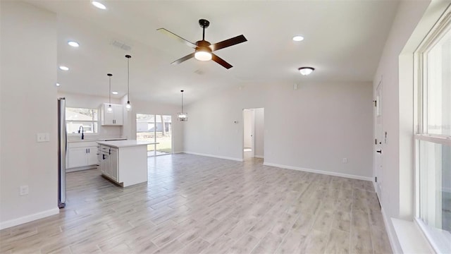 unfurnished living room with ceiling fan, sink, and light wood-type flooring