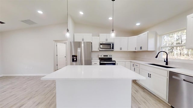 kitchen with white cabinets, a kitchen island, decorative light fixtures, stainless steel appliances, and sink