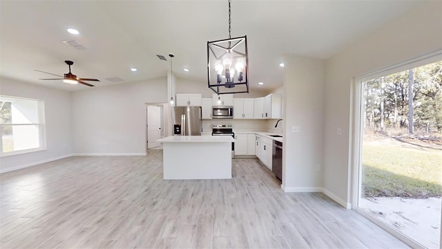 kitchen with pendant lighting, light hardwood / wood-style flooring, appliances with stainless steel finishes, white cabinetry, and a kitchen island