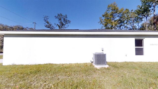 view of home's exterior with cooling unit and a lawn