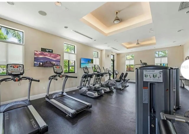 workout area with a raised ceiling and ceiling fan