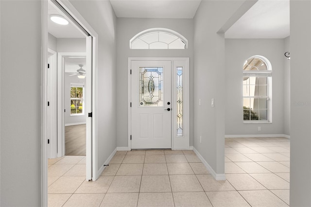 tiled entrance foyer featuring ceiling fan and a healthy amount of sunlight