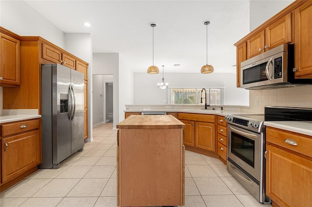 kitchen with appliances with stainless steel finishes, sink, decorative light fixtures, an inviting chandelier, and a kitchen island