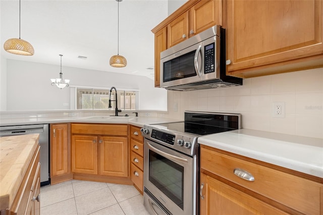 kitchen with hanging light fixtures, sink, appliances with stainless steel finishes, a notable chandelier, and light tile patterned flooring