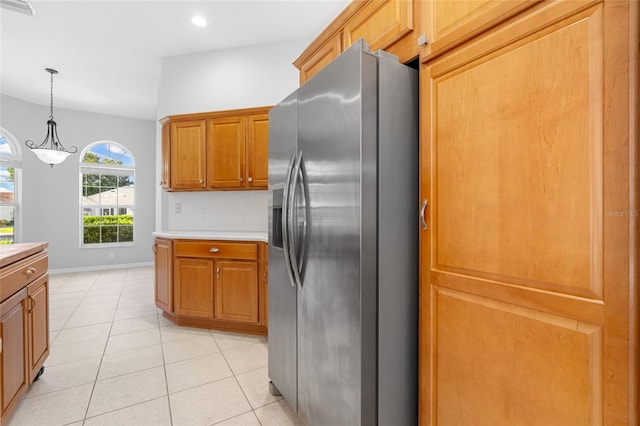 kitchen featuring pendant lighting, light tile patterned floors, and stainless steel refrigerator with ice dispenser