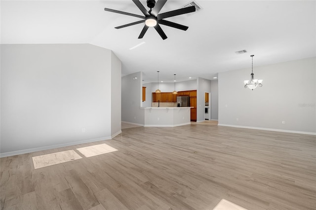 unfurnished living room with ceiling fan with notable chandelier, light hardwood / wood-style flooring, and vaulted ceiling