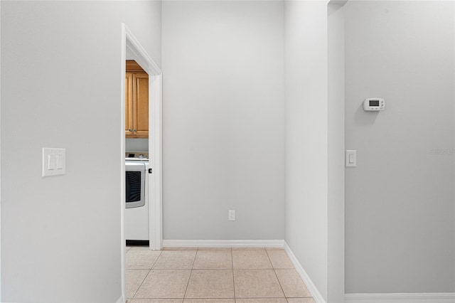 hallway with washer / dryer and light tile patterned floors