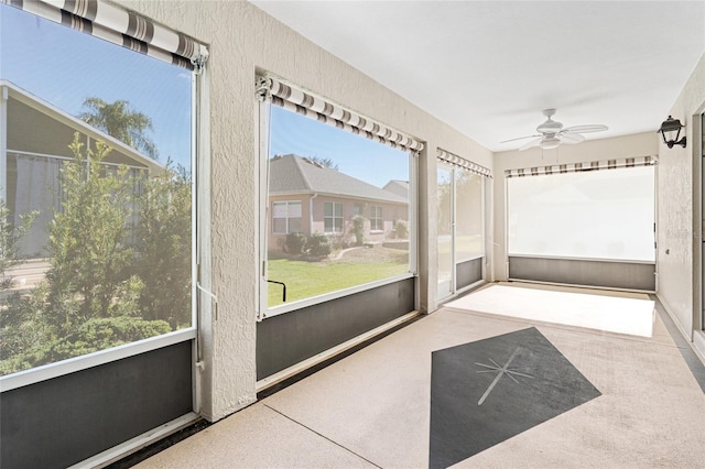 unfurnished sunroom featuring ceiling fan and a wealth of natural light