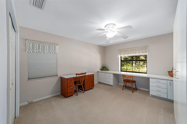 carpeted home office with built in desk and ceiling fan