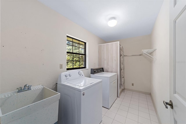 laundry area with light tile patterned floors, washer and clothes dryer, and sink