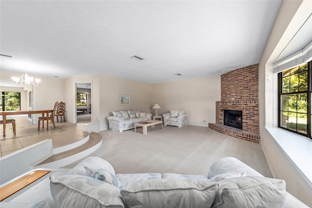 living room featuring a brick fireplace, a healthy amount of sunlight, light colored carpet, and a chandelier