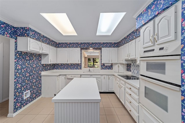 kitchen with a center island, white appliances, sink, light tile patterned floors, and white cabinetry