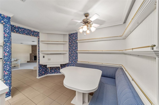 spacious closet with ceiling fan, light tile patterned floors, and a brick fireplace