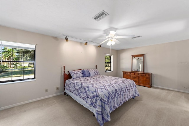 carpeted bedroom with track lighting and ceiling fan