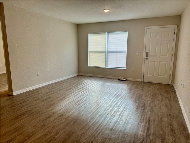 spare room featuring a textured ceiling and dark wood-type flooring