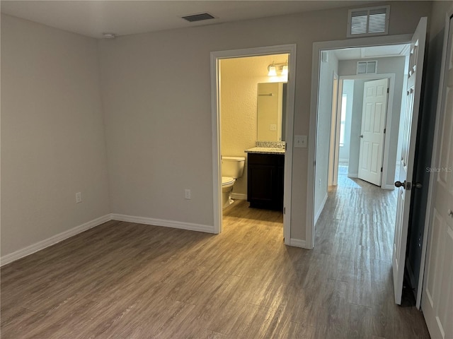 unfurnished bedroom featuring connected bathroom and light hardwood / wood-style floors