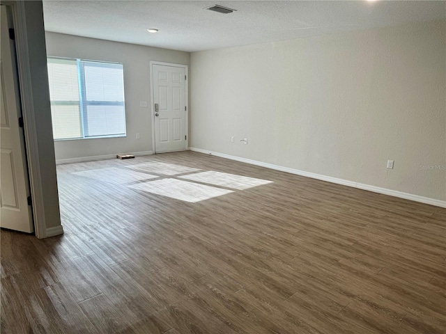 unfurnished room with dark wood-type flooring and a textured ceiling