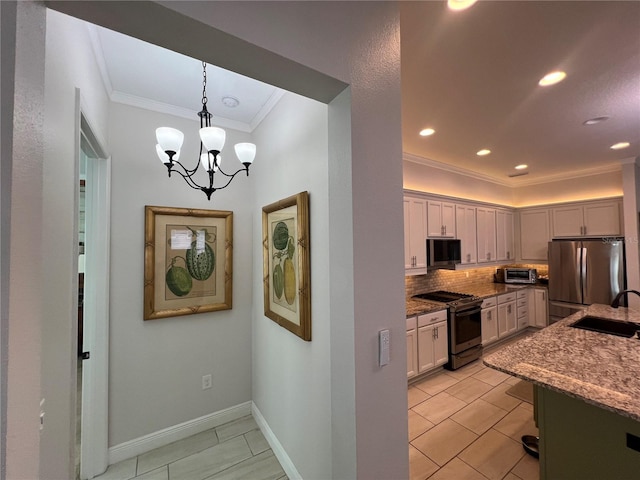 kitchen with decorative backsplash, appliances with stainless steel finishes, sink, pendant lighting, and an inviting chandelier