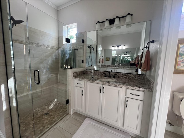 bathroom with tile patterned floors, toilet, vanity, a shower with shower door, and ornamental molding