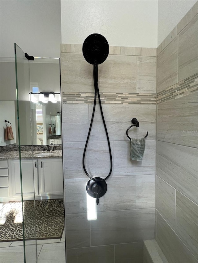 bathroom with tiled shower, vanity, and crown molding