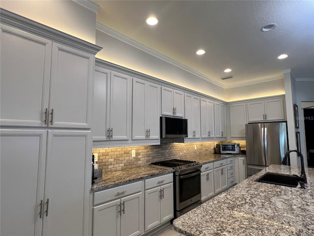 kitchen with decorative backsplash, appliances with stainless steel finishes, ornamental molding, sink, and stone counters