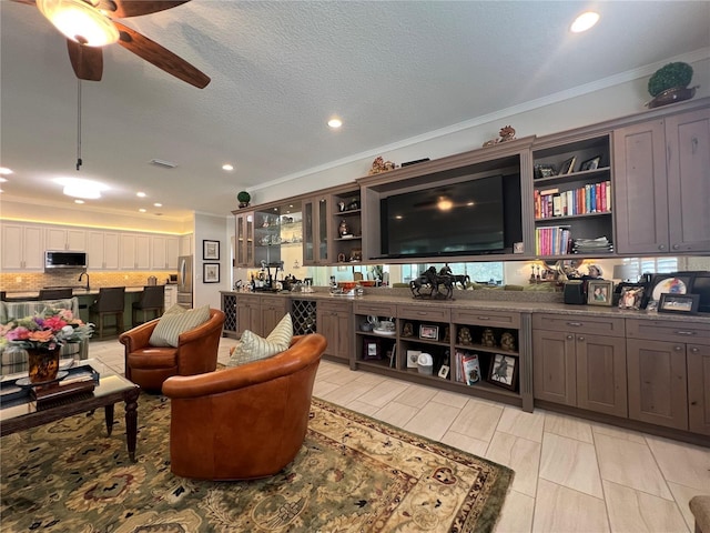 interior space featuring appliances with stainless steel finishes, backsplash, a textured ceiling, ceiling fan, and crown molding