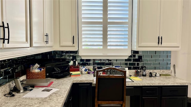 kitchen featuring light stone countertops, backsplash, and white cabinetry