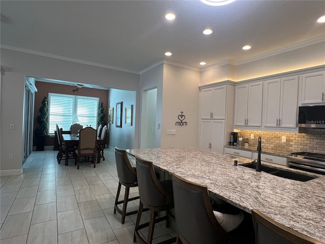 kitchen with light stone countertops, sink, decorative backsplash, white cabinets, and appliances with stainless steel finishes