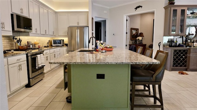 kitchen featuring a kitchen bar, light stone countertops, stainless steel appliances, sink, and a center island with sink