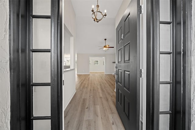 corridor with light hardwood / wood-style flooring and an inviting chandelier