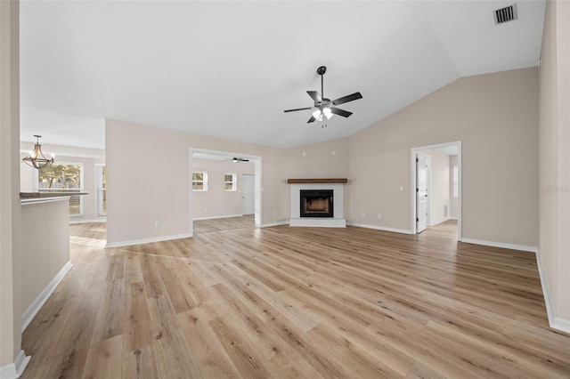 unfurnished living room with ceiling fan with notable chandelier, lofted ceiling, and light hardwood / wood-style flooring