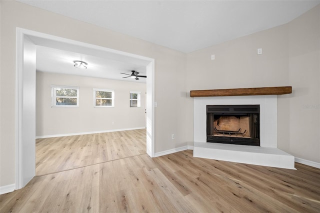 unfurnished living room with ceiling fan, a tile fireplace, and light hardwood / wood-style flooring