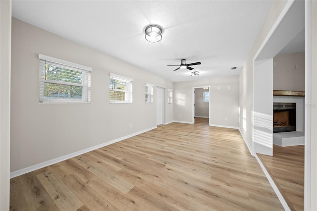 unfurnished living room featuring ceiling fan, light hardwood / wood-style floors, and a tile fireplace