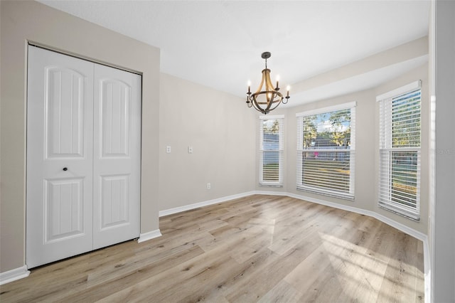 unfurnished dining area featuring light wood-type flooring and an inviting chandelier