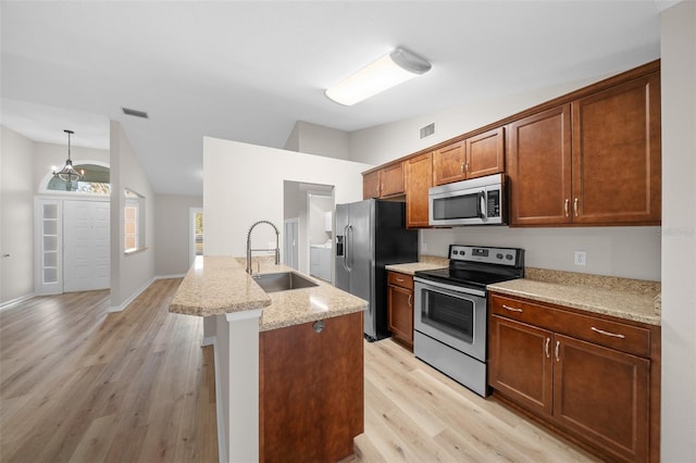 kitchen with light stone countertops, sink, an inviting chandelier, light hardwood / wood-style floors, and appliances with stainless steel finishes