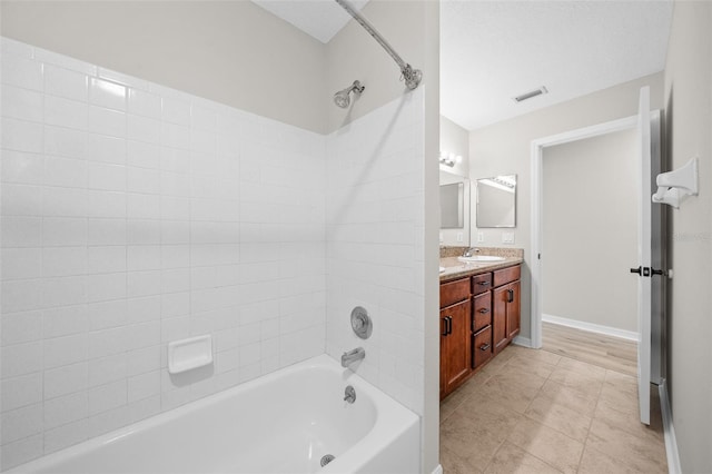 bathroom featuring tile patterned flooring, vanity, and tiled shower / bath