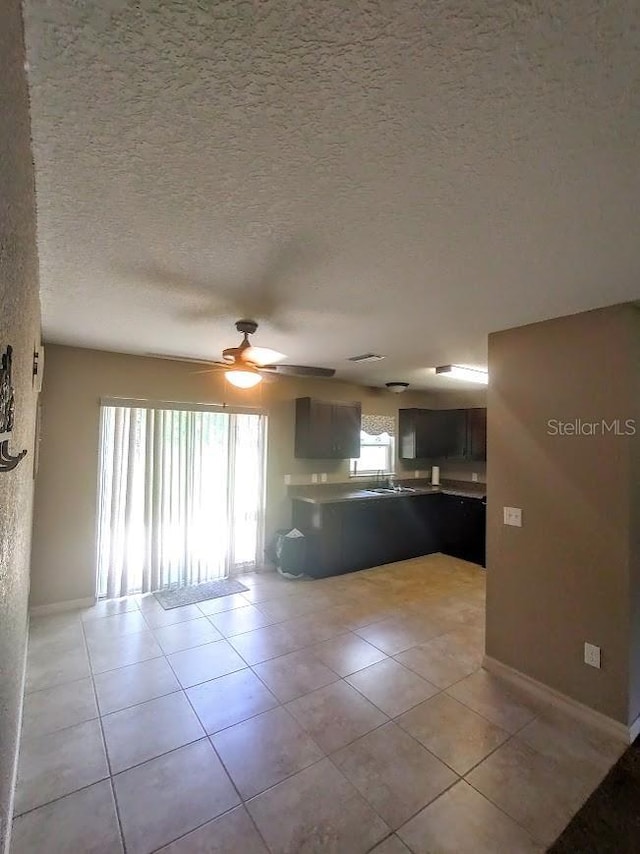 kitchen with ceiling fan, light tile patterned floors, a textured ceiling, and kitchen peninsula