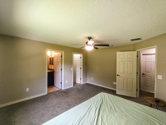 unfurnished bedroom featuring ensuite bathroom, ceiling fan, a textured ceiling, and dark carpet