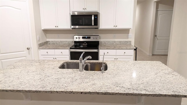 kitchen featuring appliances with stainless steel finishes, sink, white cabinets, and light stone counters