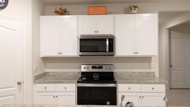 kitchen with light stone countertops, stainless steel appliances, and white cabinets