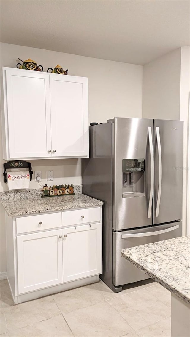 kitchen featuring white cabinetry, stainless steel fridge with ice dispenser, light stone counters, and light tile patterned floors