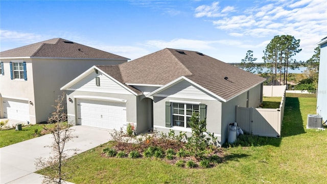 traditional-style home with a shingled roof, a front yard, driveway, and an attached garage