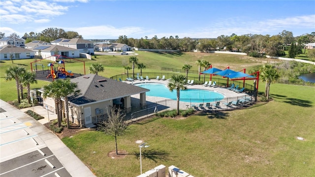 community pool featuring playground community, a yard, a patio, and fence