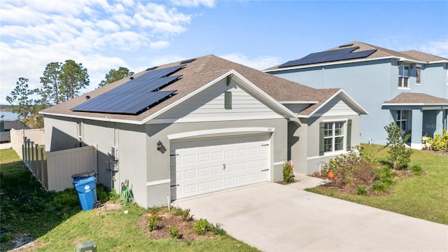 traditional home with a garage, driveway, solar panels, fence, and a front lawn