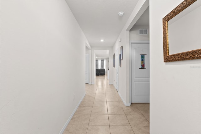 corridor with light tile patterned floors, visible vents, and baseboards