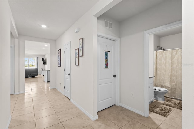 corridor featuring recessed lighting, visible vents, baseboards, and light tile patterned flooring