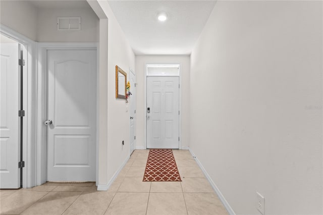 doorway with visible vents, a textured ceiling, baseboards, and light tile patterned flooring